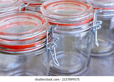 Closeup of empty glass canning jars or preserving containers with orange sealing ring in a row. Preserving food concept.            