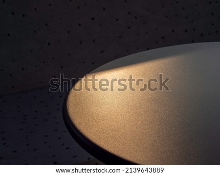 Close-up empty space for place the product object on round table edge with beautiful gold sun light on dark background.