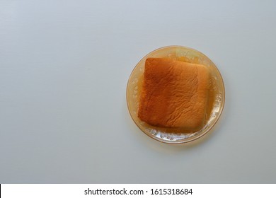 Closeup The End Slice Of Bread In Glass Plate On White Wooden Table. There Are A Few Different Names People Call It, Such As Heel, Crust. 