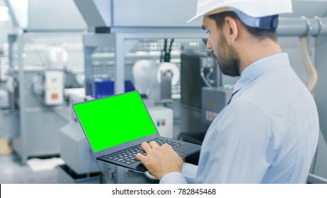 Close-up of the Engineer Holding Laptop with Green Screen Chroma Key Template Great for Mockup. In the Background Modern Factory Equipment. - Powered by Shutterstock