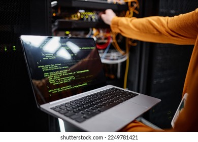 Closeup of IT engineer using laptop while setting up network in server room, copy space