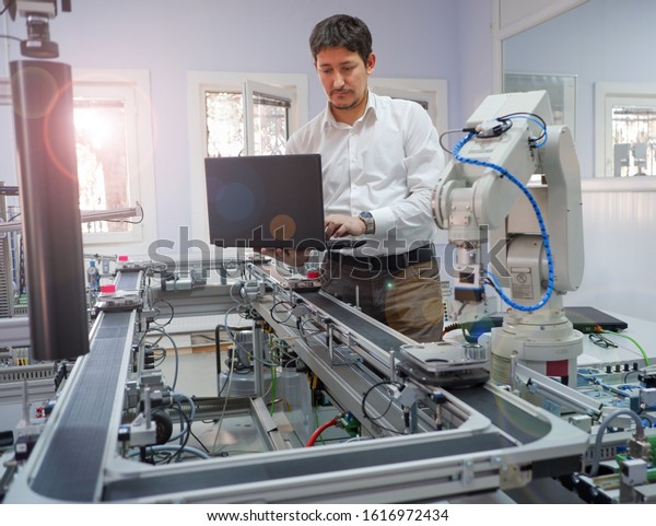 Close-up of Engineer who is working on laptop to\
programming smart factory automation and automated car on\
production line is waiting. Industry 4.0 concept; artificial\
intelligence in smart\
factory.