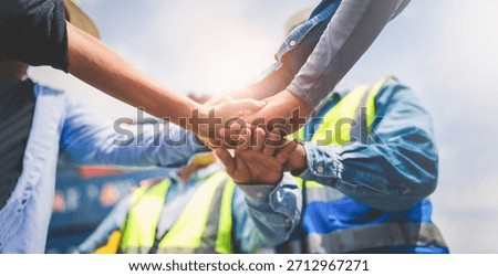 Close-up of Engineering team making pile of hands with cargo container background at sunset. Logistics global import or export shipping industrial concept.