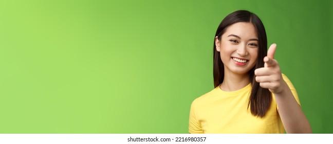 Close-up entertained outgoing asian brunette female having fun congratulate you, pointing you camera laughing, joyfully chat, having friendly conversation, gree background. Copy space