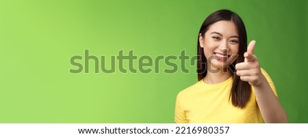 Close-up entertained outgoing asian brunette female having fun congratulate you, pointing you camera laughing, joyfully chat, having friendly conversation, gree background. Copy space