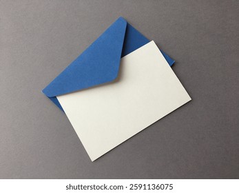 Close-up of an envelope with a message. White blank card and blue envelope on gray background