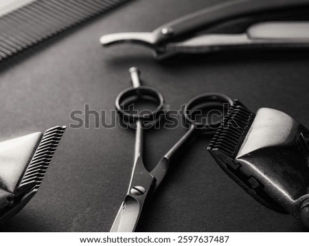 Close-up of essential barber tools including scissors, clippers, and a comb on a dark surface, showcasing the precision instruments used for grooming and hairstyling.