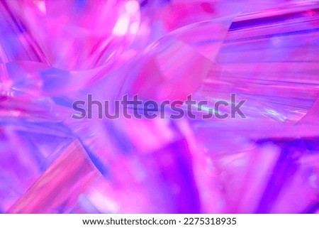 Close-up of ethereal bright neon blue, purple, lavender, pink holographic metallic foil background. Abstract modern curved blurred surreal futuristic disco, rave, techno, festive dreamlike backdrop