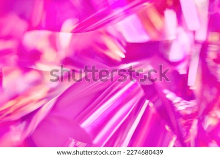 Close-up of ethereal bright neon pink, magenta, orange holographic metallic foil background. Abstract modern curved blurred surreal futuristic disco, rave, techno, festive dreamlike backdrop