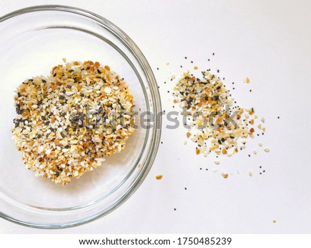 Closeup of everything but the bagel seasoning mix in a glass bowl (includes sesame seeds, onion, garlic flakes, salt, poppy seeds)
