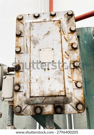 Close-up of an explosion proof electrical junction box installed in an industrial facility, showing corrosion and weathering signs for maintenance inspection, safety compliance and hazardous area operations.
