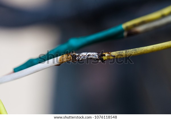 Closeup of exposed live electrical\
wire with melted insulation/electrical fire danger\
concept
