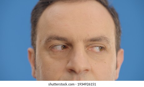 Close-up Eye In Front Of A Blue Background, Young Man Moving His Eyes Left And Right. Looking Left And Right, Up And Down With His Eyes.