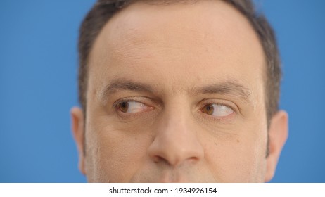 Close-up Eye In Front Of A Blue Background, Young Man Moving His Eyes Left And Right. Looking Left And Right, Up And Down With His Eyes.