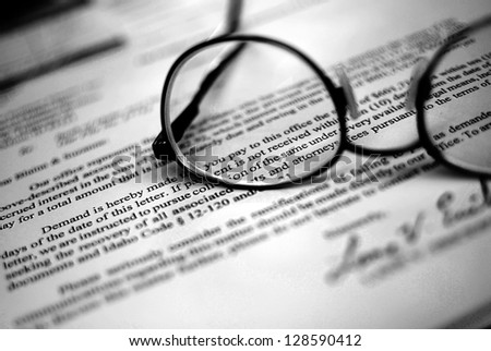 Closeup of Eyeglasses on top of business document with signature