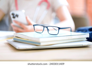 Closeup eyeglasses placed on top of textbooks on a medical student's desk and blurred of medical student relaxing background. Education concept