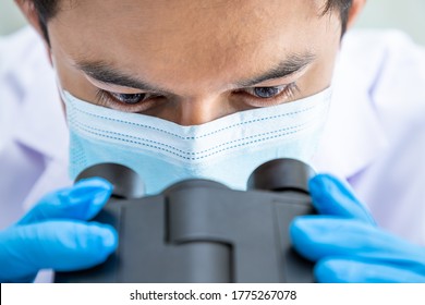 Close-up Eyes Asian Male Researcher Scientist Medical Doctor Wearing Surgical Mask Looking Through Microscope