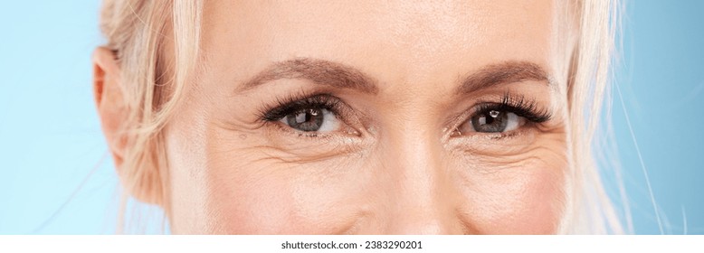 Closeup, eyes and old woman with skincare, cosmetics and wrinkles against blue studio background. Zoom, mature female and senior lady with eyecare, dermatology and beauty with wellness on backdrop - Powered by Shutterstock