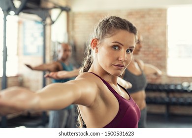 Closeup Face Of Determined Woman Doing Aerobic Exercises At Gym Standing With Arms Outstretched. Determined Young Woman In Sportswear Stretching Arms In Gym. Beautiful Girl In Yoga Pose With Class.