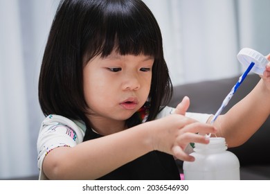 Closeup Face Girl Learning Craft In Classroom. Kindergarten Pupil Touching Glue For Doing Invention. Preschool Kid With Fun DIY Project. Baby Aged 4-5 Years Old Wearing Black Apron.