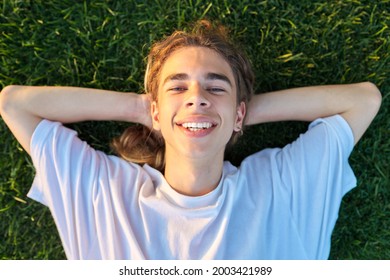 Close-up Face Of Handsome Guy 16, 17 Years Old On Green Grass, Top View