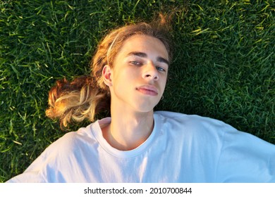 Close-up Face Of Handsome Guy 16, 17 Years Old On Green Grass, Top View