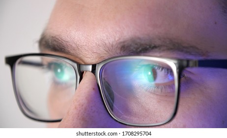 Close-up Face Of A Male Eyes With Glasses Works At The Computer. Display Reflection In Glasses. Portrait Of A Young Man Programmer With Glasses. Work In Home. Quarantine