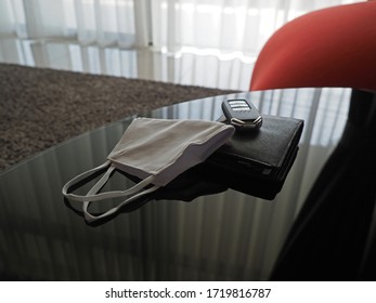 Closeup Of A Face Mask, Wallet And Car Key On A Black Gloss Table At Home.