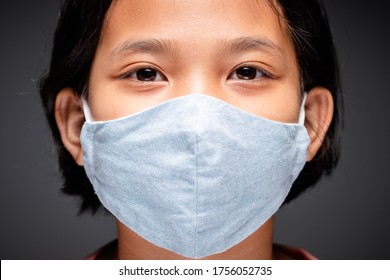 Closeup Face Of Nine Years Old Child Wearing Blue Cloth Mask And Looking At Camera, Asian Child Prevent Pandemic Of Covid-19