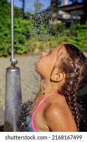Close-up face of pretty girl takes shower on the beach in the summer camp, refreshing in cold water, enjoying summer vacation on the sea resort, family travel and recreation
