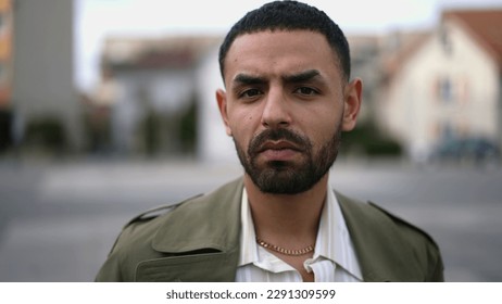 Closeup face of a serious Middle Eastern man looking at camera standing in urban environment - Shutterstock ID 2291309599