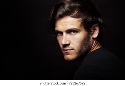 Close-up face of young bearded man on dark background modern and dramatic photo