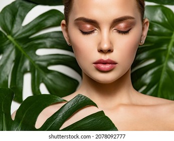 Closeup face of young beautiful woman with a healthy clean skin. Beautiful white girl with big green leaves. Beauty and spa treatment concept. Pretty woman with natural makeup and plant near face - Shutterstock ID 2078092777