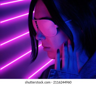 Close-up Face Of A Young Woman In Pink Glasses In Neon Pink Light. Concept Synthwave Or Retrowave.