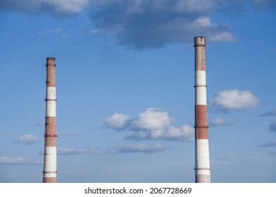 Close-up Factory Brick Chimney. Two Pipes Cogeneration Plant On The Sky Background. Ambient Air Pollution Industrial Emissions.