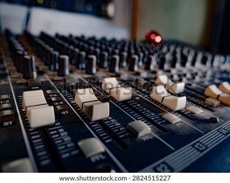Close-up of faders and knobs on a professional analog sound mixing console in a music recording studio