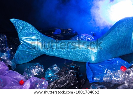 Close-up of fairytale mermaid in polluted ocean. Plastic trash and garbage in water. Environmental problem, plastic bag and bottles polluting a coral reef.