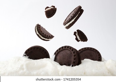 Closeup of falling delicious chocolate sandwich cookies and sweet glaze against white background