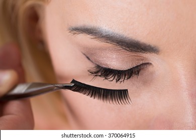 Close-up of false eyelashes being put on woman's eye