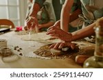 Close-up of family baking cookies together, hands busy with rolling and cutting dough on a kitchen counter, showing teamwork, joy, and love in the process of cooking