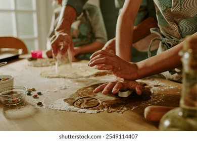 Close-up of family baking cookies together, hands busy with rolling and cutting dough on a kitchen counter, showing teamwork, joy, and love in the process of cooking - Powered by Shutterstock