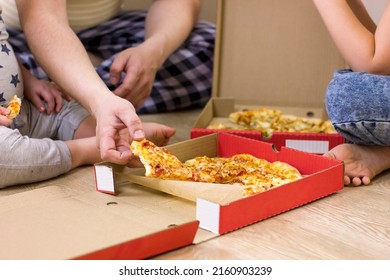 Closeup family hands taking pizza slices on wooden floor background. Food delivery service. Happy together. Father and children eating pizza at home. Focus picked.