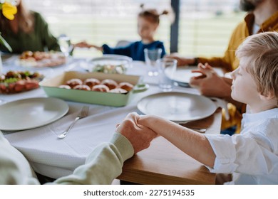 Close-up of family holding hands, praying before Easter lunch. - Powered by Shutterstock