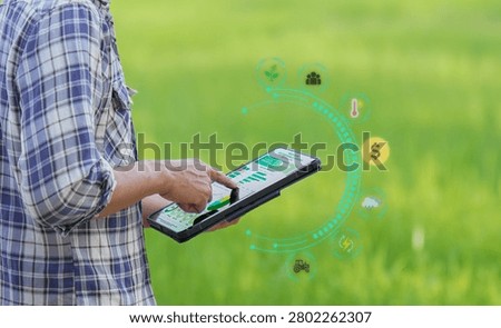A close-up of a farmer's hand using a digital tablet to analyze agricultural data, crop statistics, and financial metrics represented by a modern digital overlay interface. This image symbolizes precision agriculture, data-driven farming, innovation, and technological advancements in the agricultural sector.