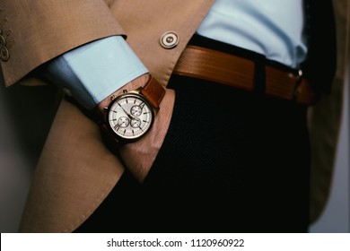 Closeup Fashion Image Of Luxury Brown  Watch On Wrist Of Man.body Detail Of A Business Man.Man's Hand In Pants Pocket Closeup At White Background.Man Wearing Beige Jacket And White Shirt.Not Isolated