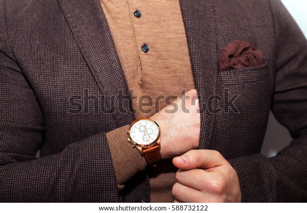 Closeup fashion image of
luxury watch on wrist of man.body detail of a business man.Man's
hand in a brown beige wool suit  closeup at white background.Not
isolated