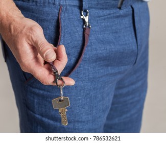 Closeup fashion image of man holding keys in his hand. Stylish jeans and keys. Man taking keys out of his pocket. Safety concept of man holding keys.