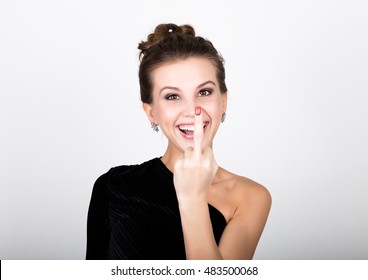 close-up fashion photo of young lady in elegant black dress, playful woman smiling and showing middle finger