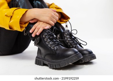 Close-up Fashion Shoes. Girl On Studio Floor In A Leather Mustard Jacket, Black Snake Texture Leggings And Boots. High Fashion, Isolated Against A Studio Background