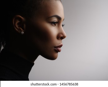 Closeup Fashionable Portrait Of A Metis Young Woman With Perfect Smooth Glowing Skin, Full Lips, Collected Hair And Long Neck. Studio Photo Of An African American Female Model Face, Profile